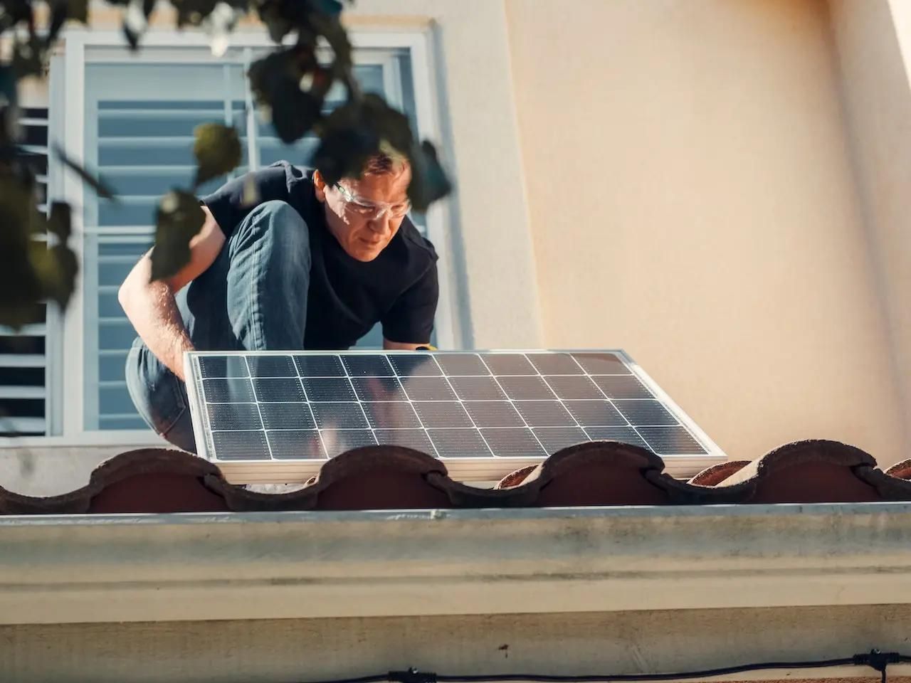 Ein Solarpanel wird von einem Handwerker auf einem Dach montiert.