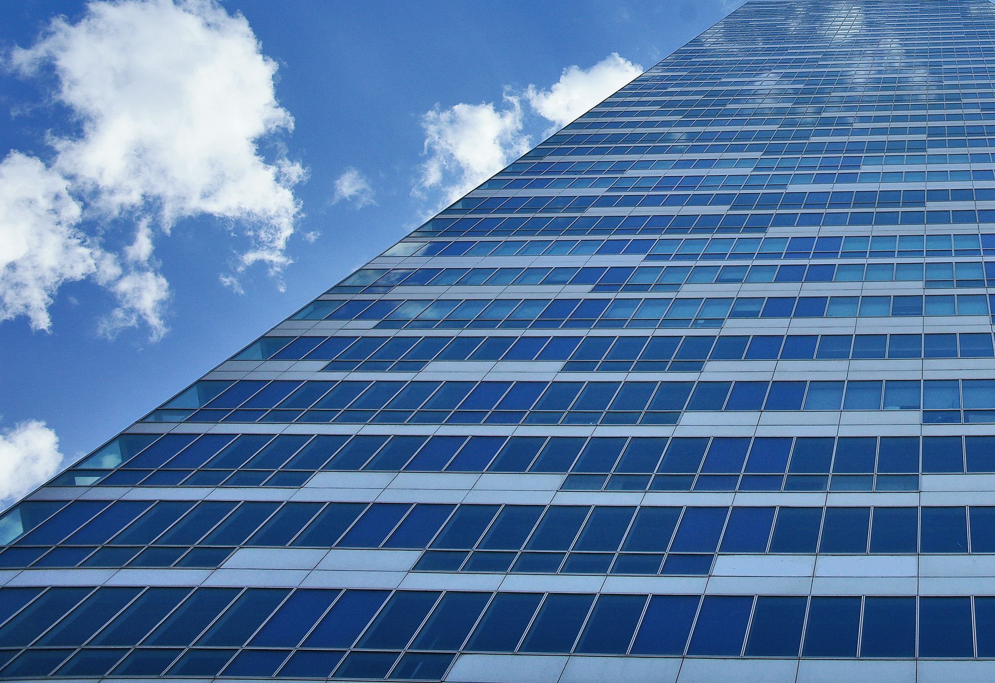Hochhaus mit Fassade aus Glas und Solarmodulen in Blautönen vor leicht bewölktem Himmel