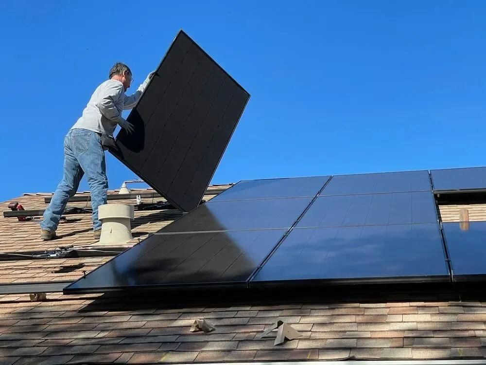 Installateur auf einem Dach mit Solarpanel in der Hand