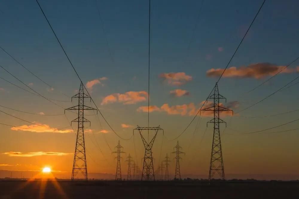Strommaste auf freiem Feld im Lichte eines Sonnenuntergangs