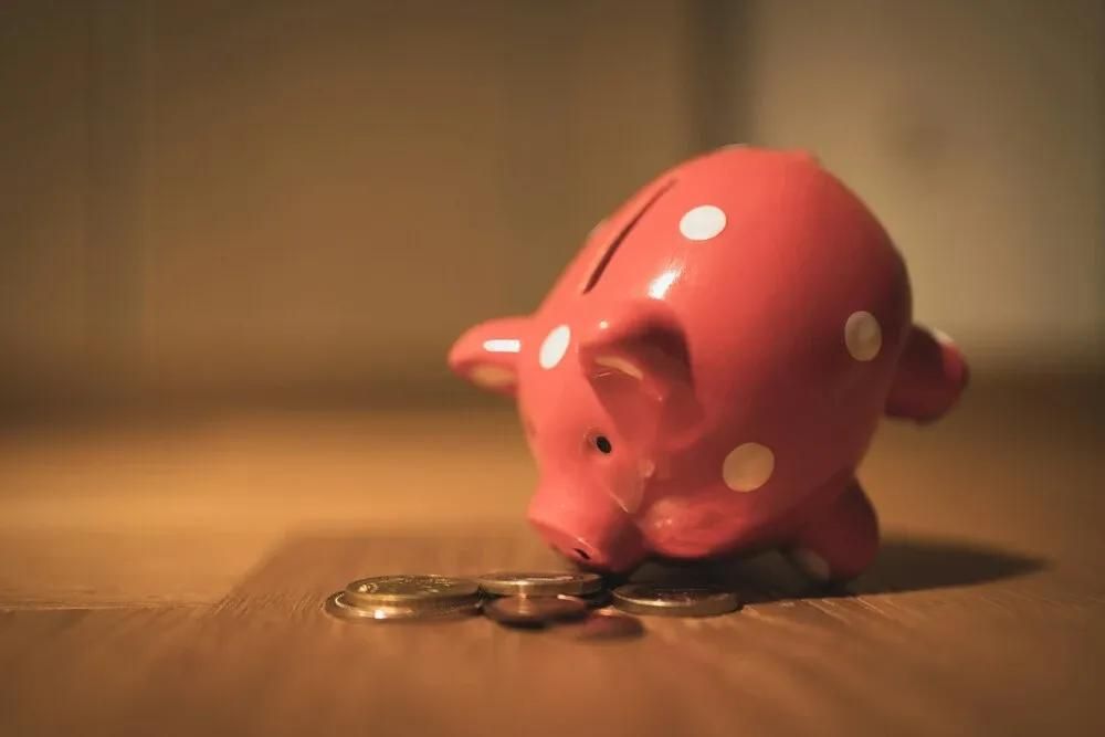 rotes Sparschwein mit weißen Punkten nach vorne gekippt auf Münzen