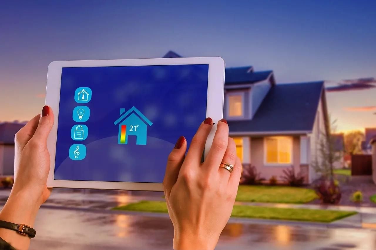 Tablet mit Energiemanagementsystem-App und Haus im Hintergrund